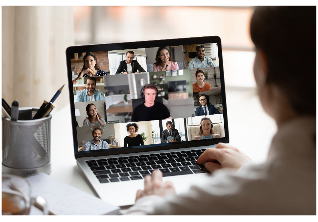 A person participates in a video conference on a laptop with multiple people visible on the screen.