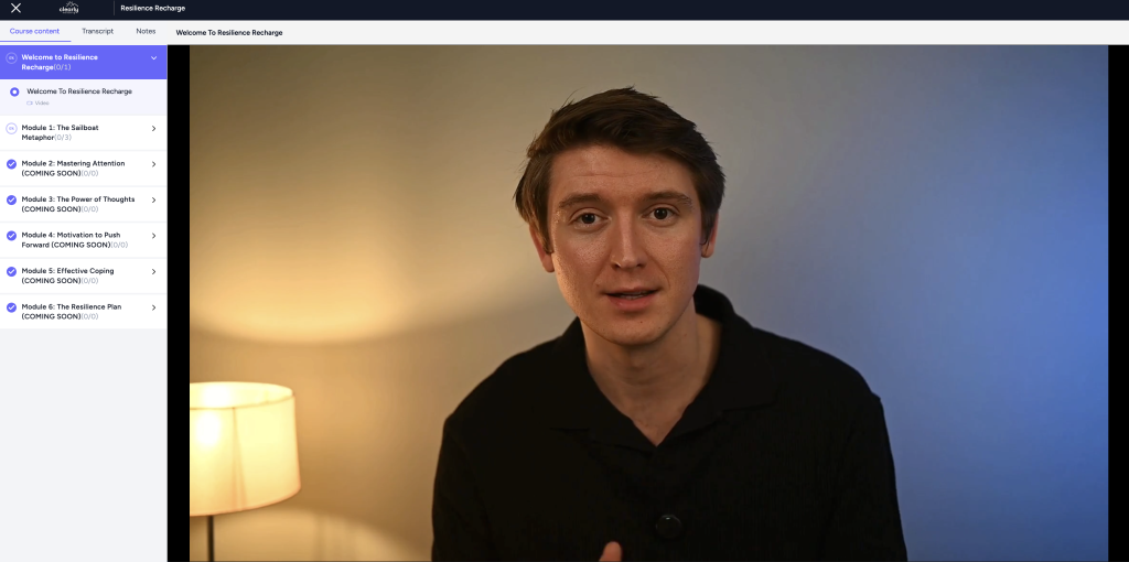 A man sits in a dimly lit room next to a lamp, facing the camera. An online course menu is visible on the left side of the screen.